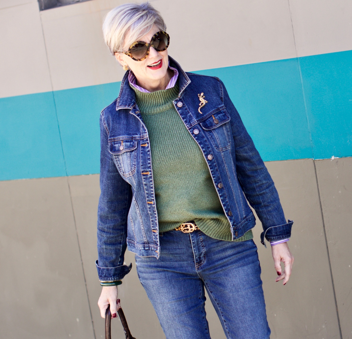 beth from Style at a Certain Age wears a chunky turtleneck layered over a stripe button down, skinny ankle jeans, a denim jacket, and booties