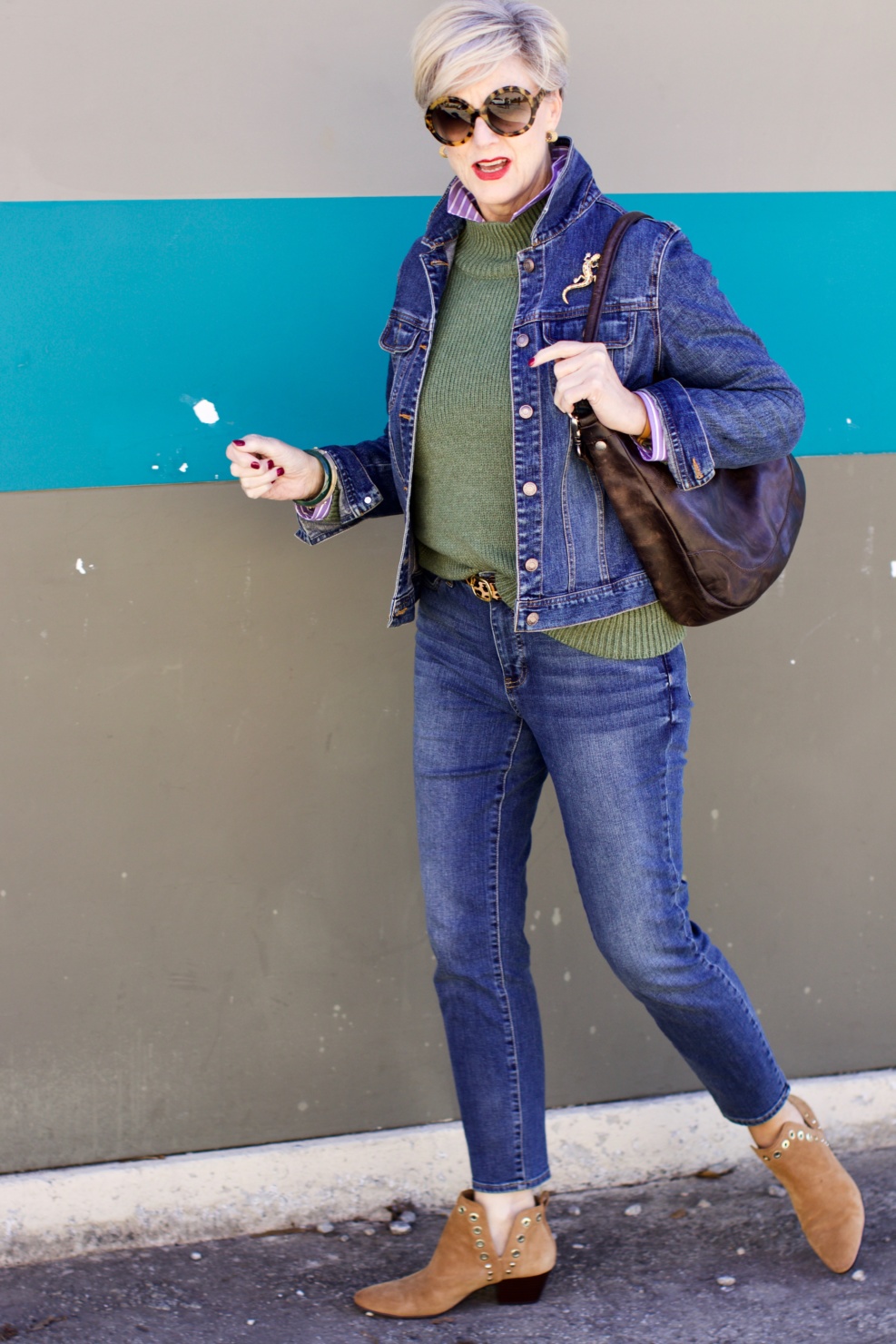 beth from Style at a Certain Age wears a chunky turtleneck layered over a stripe button down, skinny ankle jeans, a denim jacket, and booties