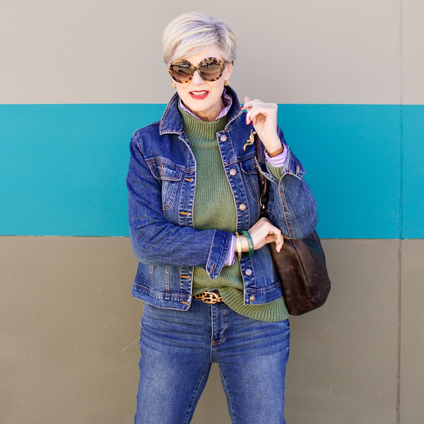 beth from Style at a Certain Age wears a chunky turtleneck layered over a stripe button down, skinny ankle jeans, a denim jacket, and booties