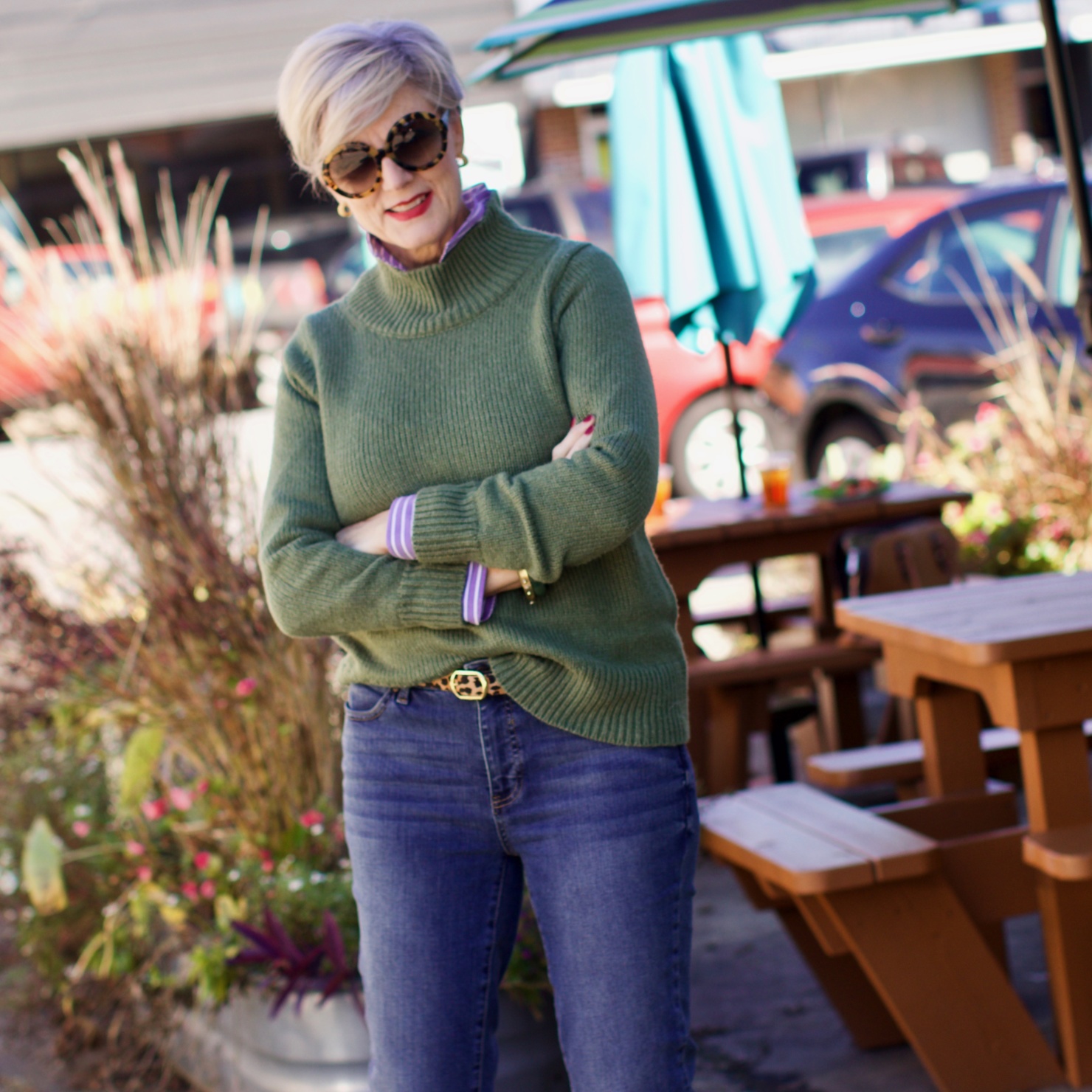 beth from Style at a Certain Age wears a chunky turtleneck layered over a stripe button down, skinny ankle jeans, a denim jacket, and booties