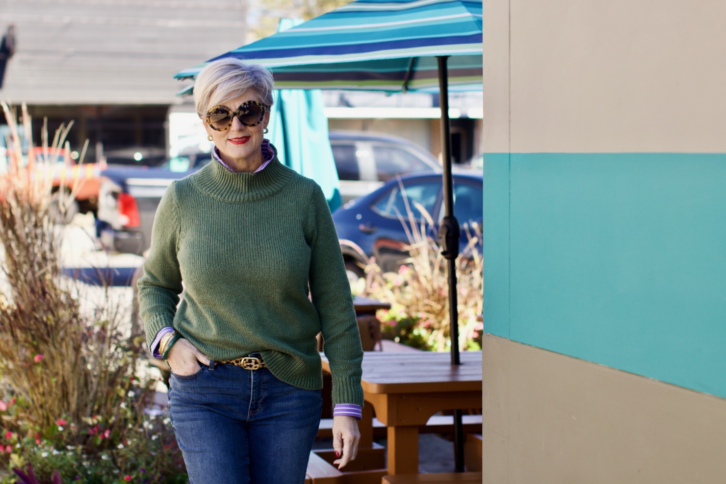 beth from Style at a Certain Age wears a chunky turtleneck layered over a stripe button down, skinny ankle jeans, a denim jacket, and booties