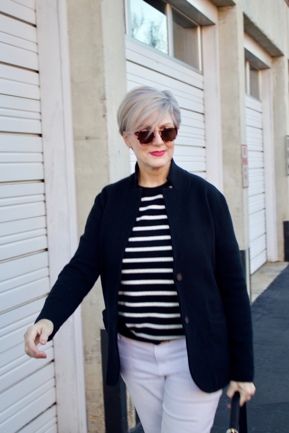 beth from Style at a Certain Age wears a red stadium coat, houndstooth cashmere scarf, white denim, striped cashmere crewneck, black ankle boots and quilted hobo handbag