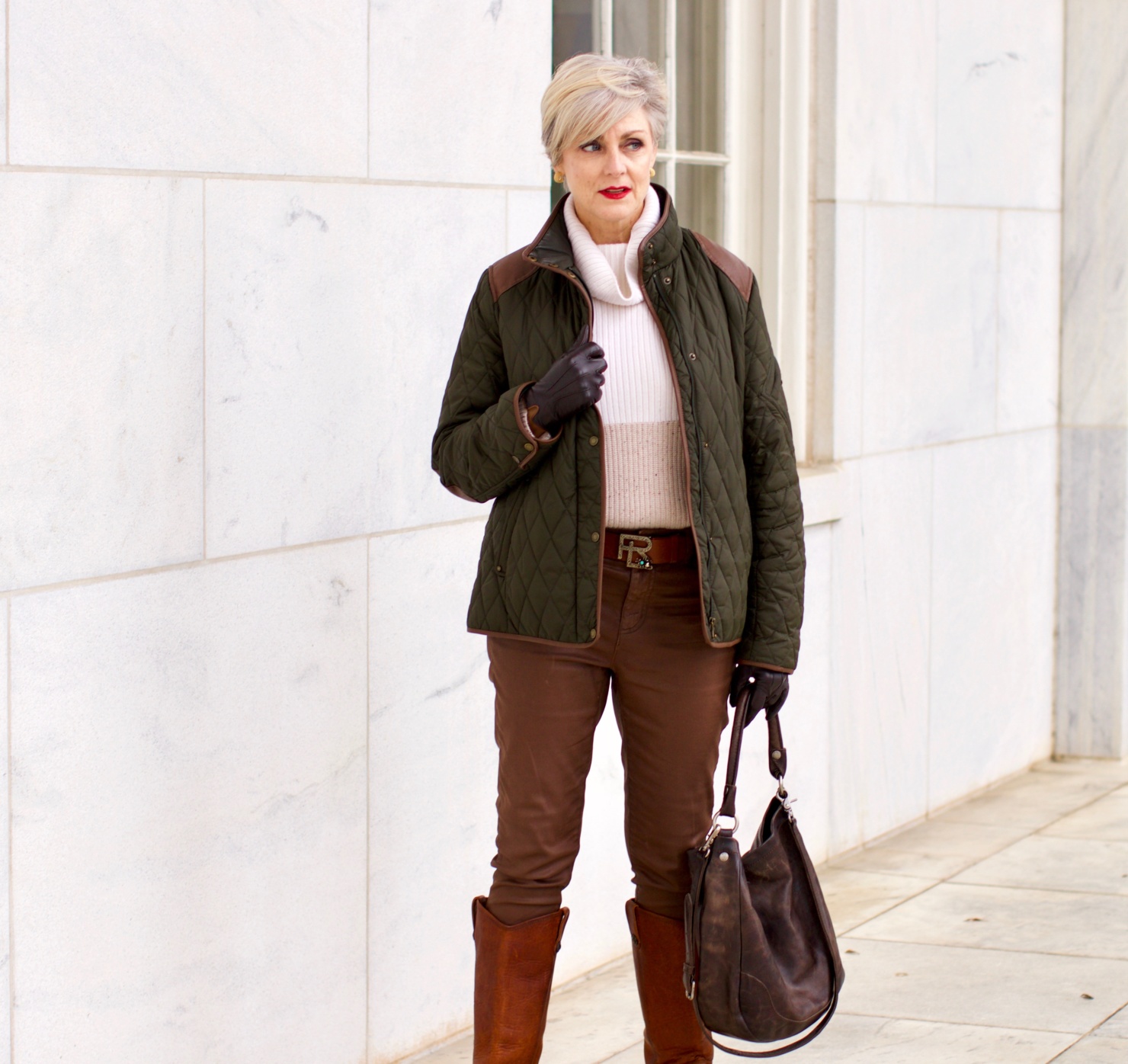 beth from Style at a Certain Age is wearing Ralph Lauren faux leather pants, chunky cashmere sweater, green utility jacket, Frye boots, and Frye hobo handbag