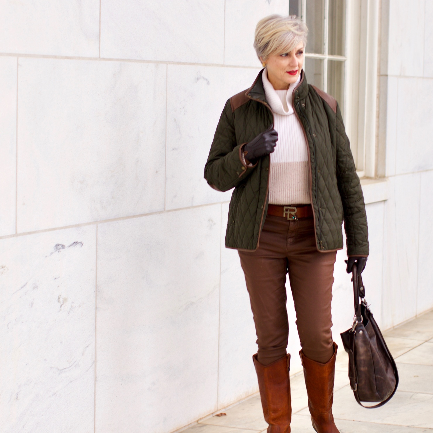 beth from Style at a Certain Age is wearing Ralph Lauren faux leather pants, chunky cashmere sweater, green utility jacket, Frye boots, and Frye hobo handbag