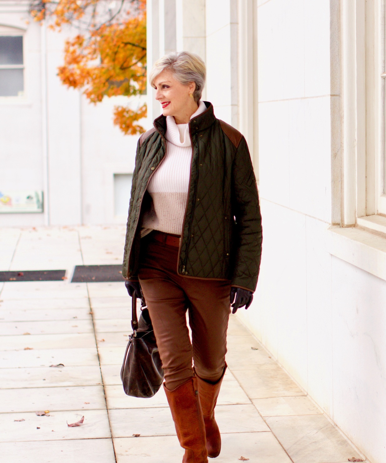 beth from Style at a Certain Age is wearing Ralph Lauren faux leather pants, chunky cashmere sweater, green utility jacket, Frye boots, and Frye hobo handbag