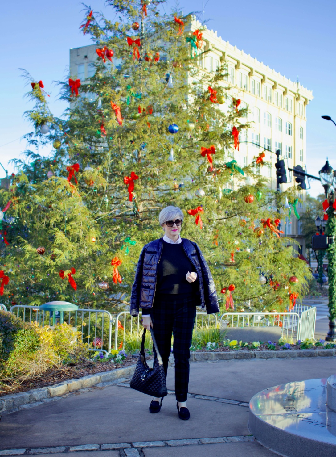 beth from Style at a Certain Age wears a Talbots navy puffer jacket, black watch plaid ankle pants, Everlane cashmere crewneck 