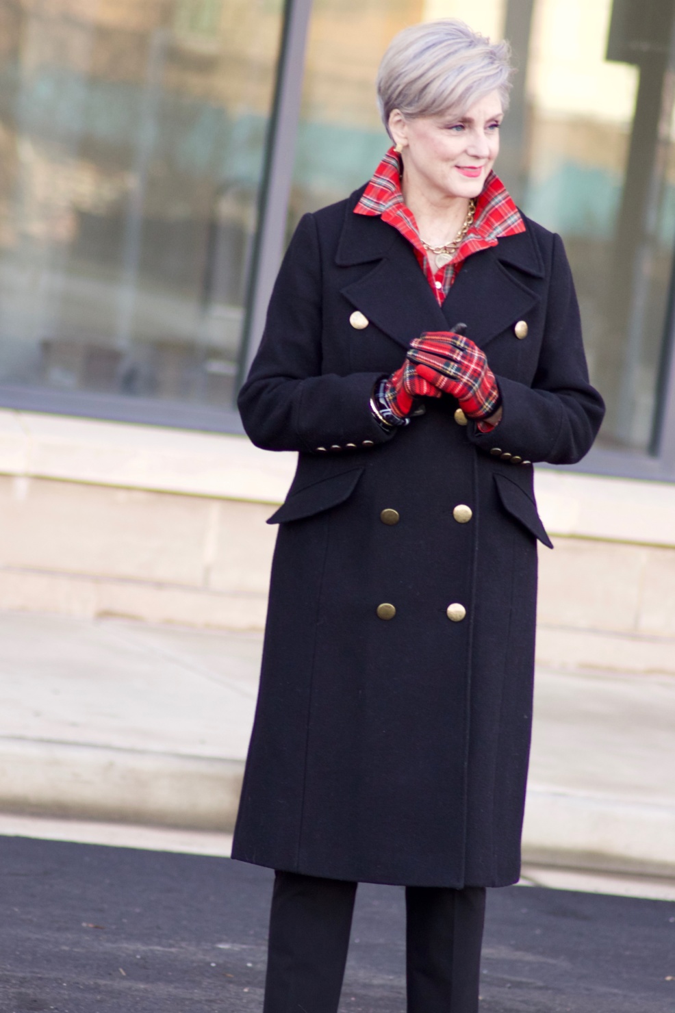 beth from Style at a Certain Age wears a tartan plaid shirt, black cropped ankle pants, tartan plaid flats, military coat and quilted hobo handbag.