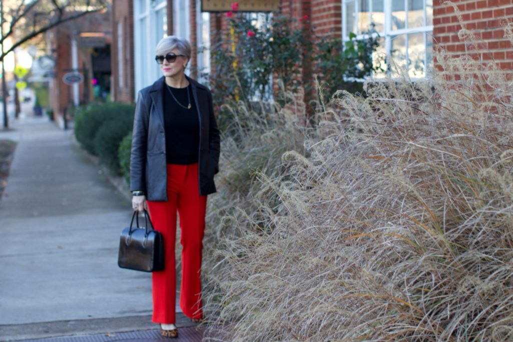 beth from Style at a Certain Age wears Anthropologie red pants, Everlane black cashmere crewneck, black leather blazer, and leopard pumps