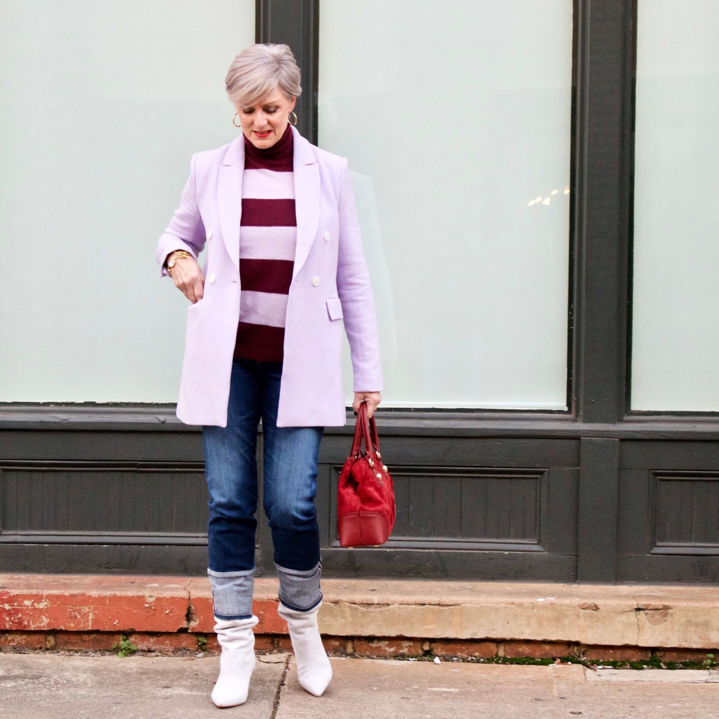 beth from Style at a Certain Age wears a striped turtleneck, lilac blazer, cuffed denim, grey suede boots