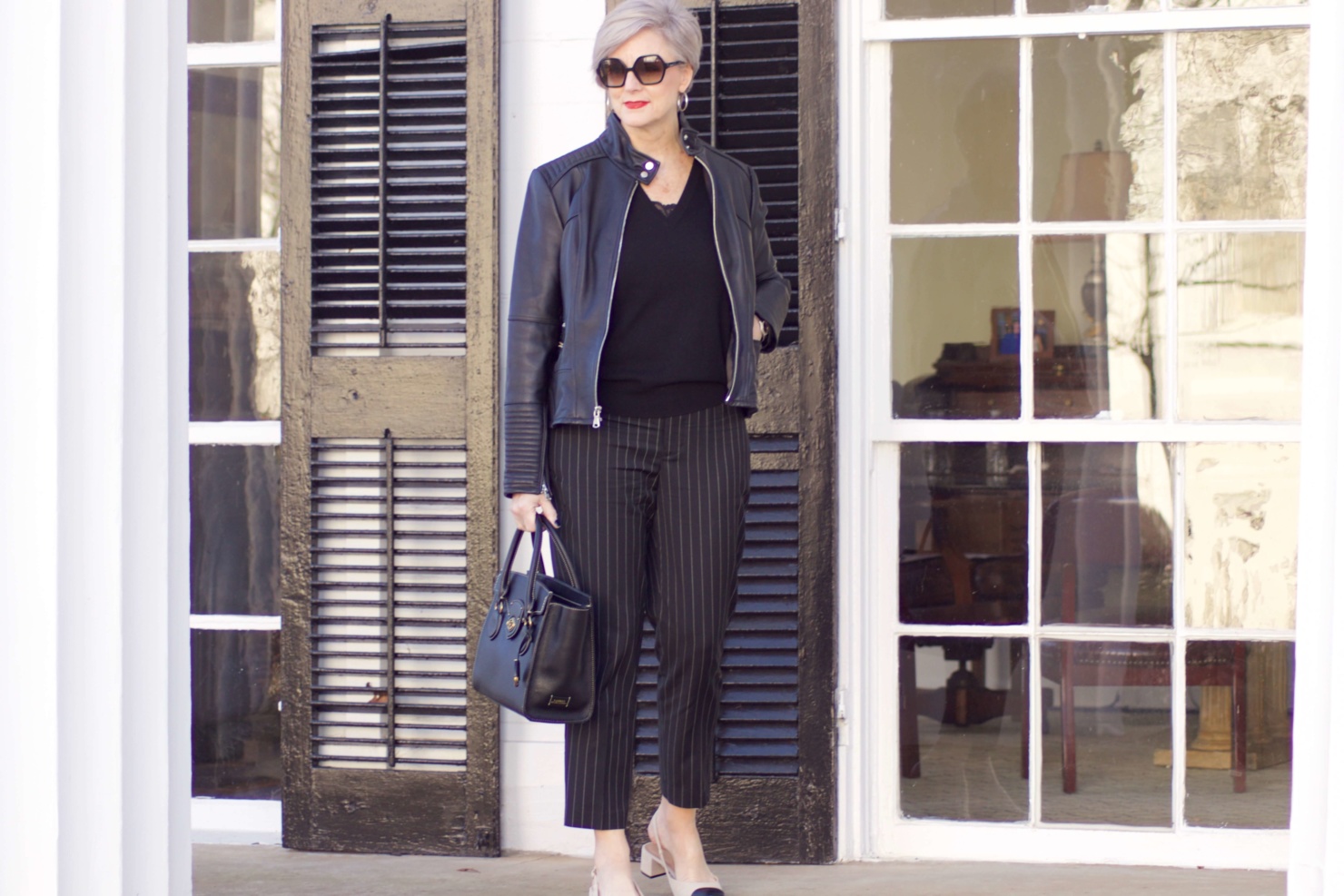 beth from Style at a Certain Age wears Ralph Lauren pinstripe pants, Everlane cashmere sweater, black leather moto jacket, and cap toe slingbacks