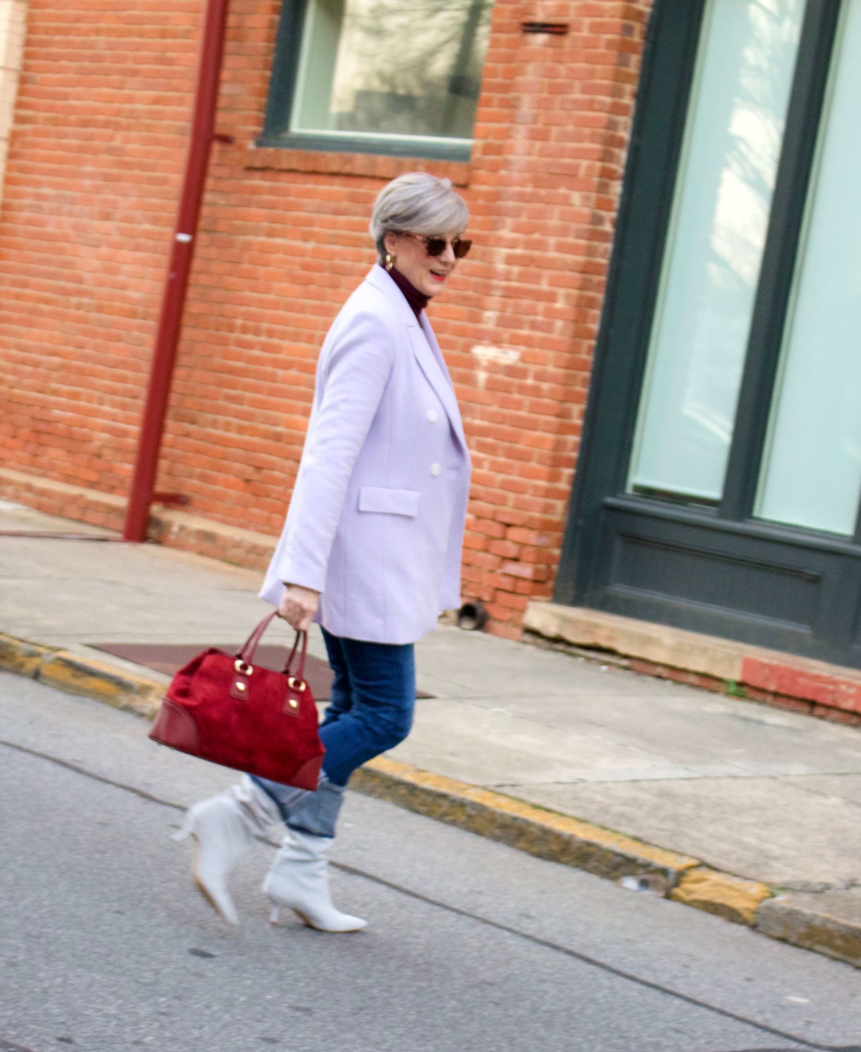 beth from Style at a Certain Age wears a striped turtleneck, lilac blazer, cuffed denim, grey suede boots