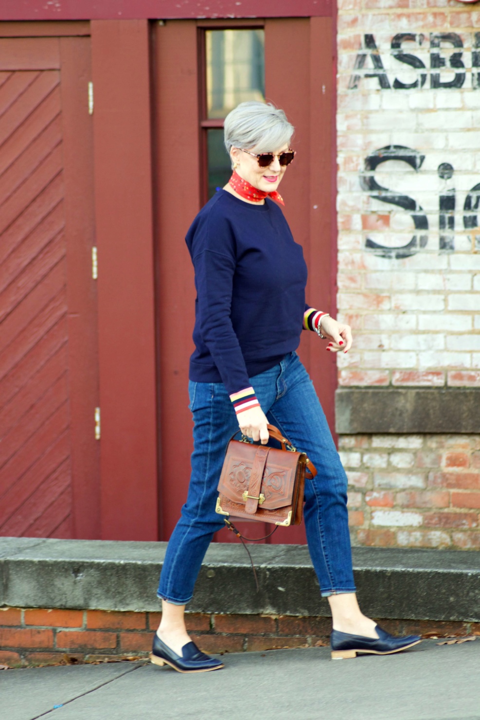 beth from Style at a Certain Age wears a navy blue sweatshirt, blue jeans, Everlane loafers and a J.Crew scarf