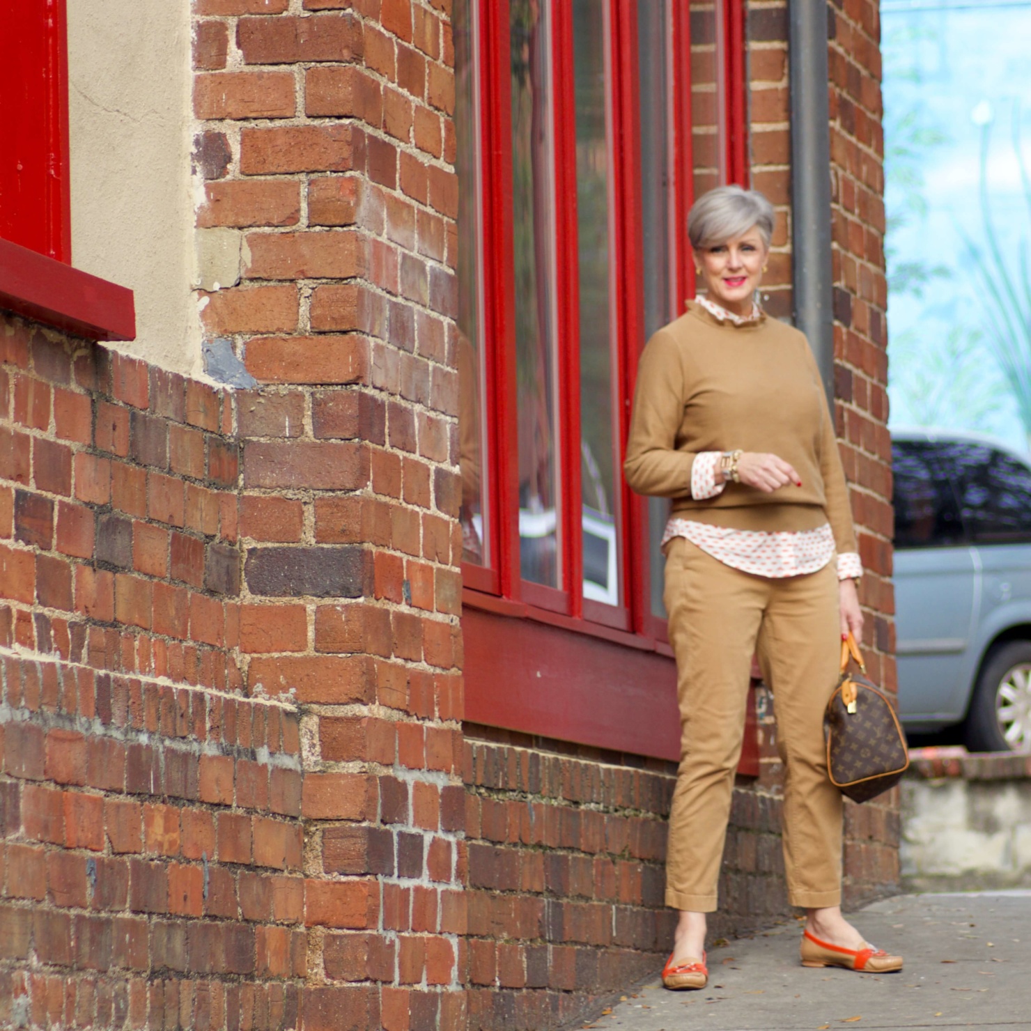 beth from Style at a Certain Age wears a J.Crew camel ruffle neck sweater, slim boy chinos and a Boden modern classic shirt with a bold print.