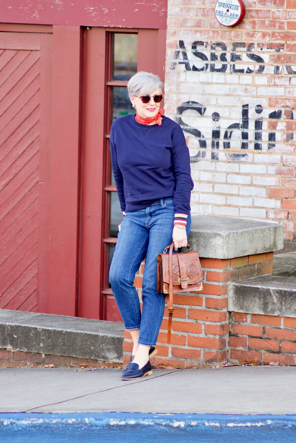 beth from Style at a Certain Age wears a navy blue sweatshirt, blue jeans, Everlane loafers and a J.Crew scarf