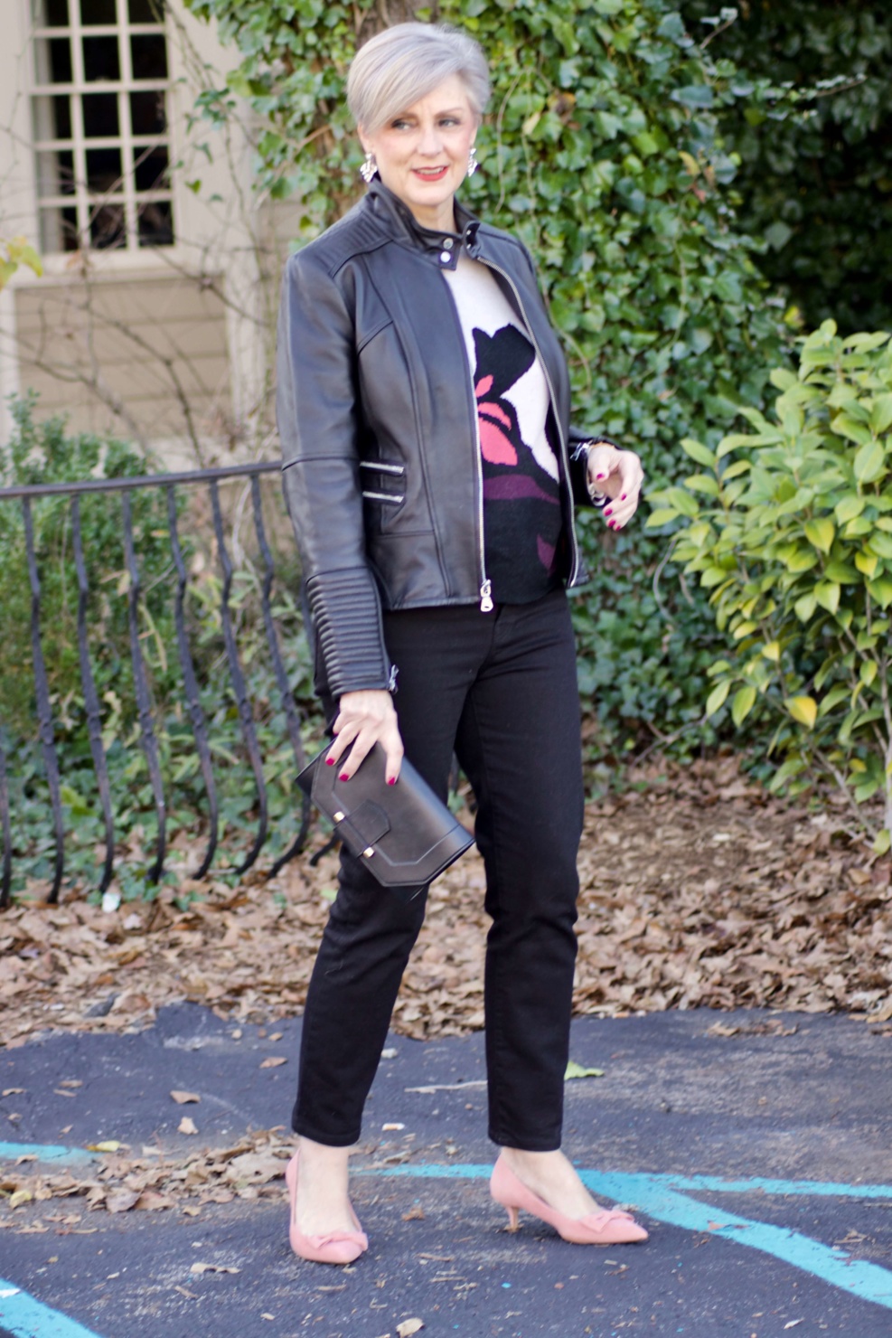 beth from Style at a Certain Age wears a floral jacquard sweater, black skinny jeans, black leather moto jacket and pink suede pumps for date night