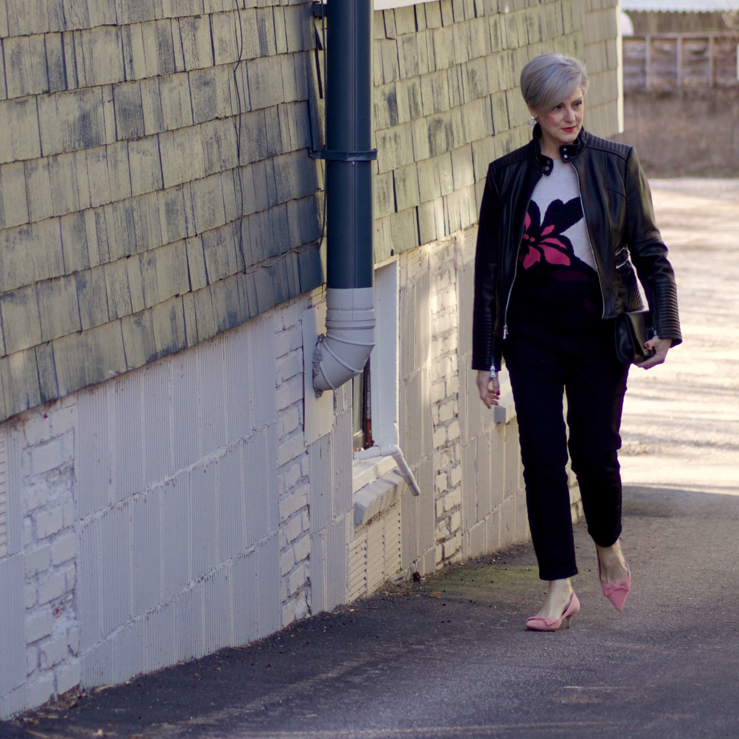 beth from Style at a Certain Age wears a floral jacquard sweater, black skinny jeans, black leather moto jacket and pink suede pumps for date night