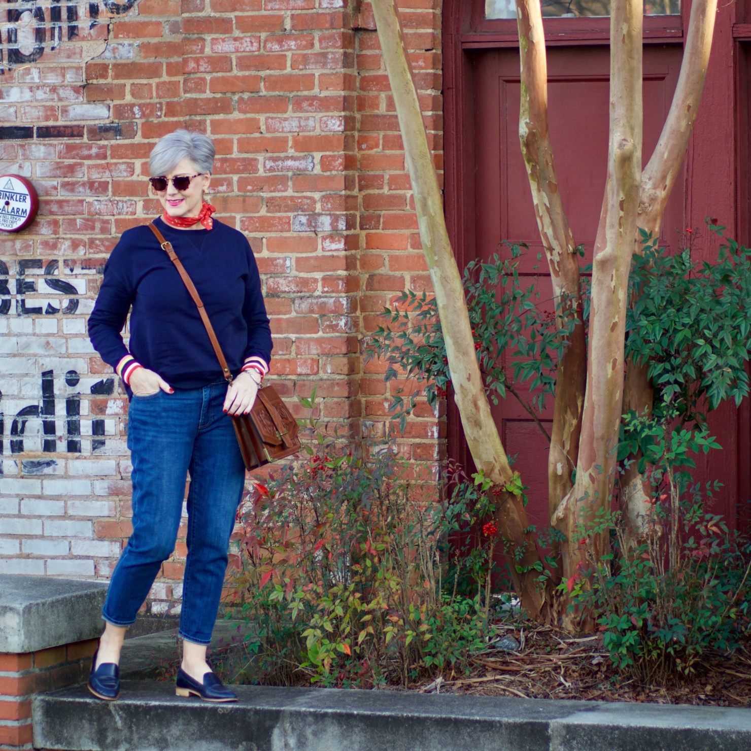 beth from Style at a Certain Age wears a navy blue sweatshirt, blue jeans, Everlane loafers and a J.Crew scarf