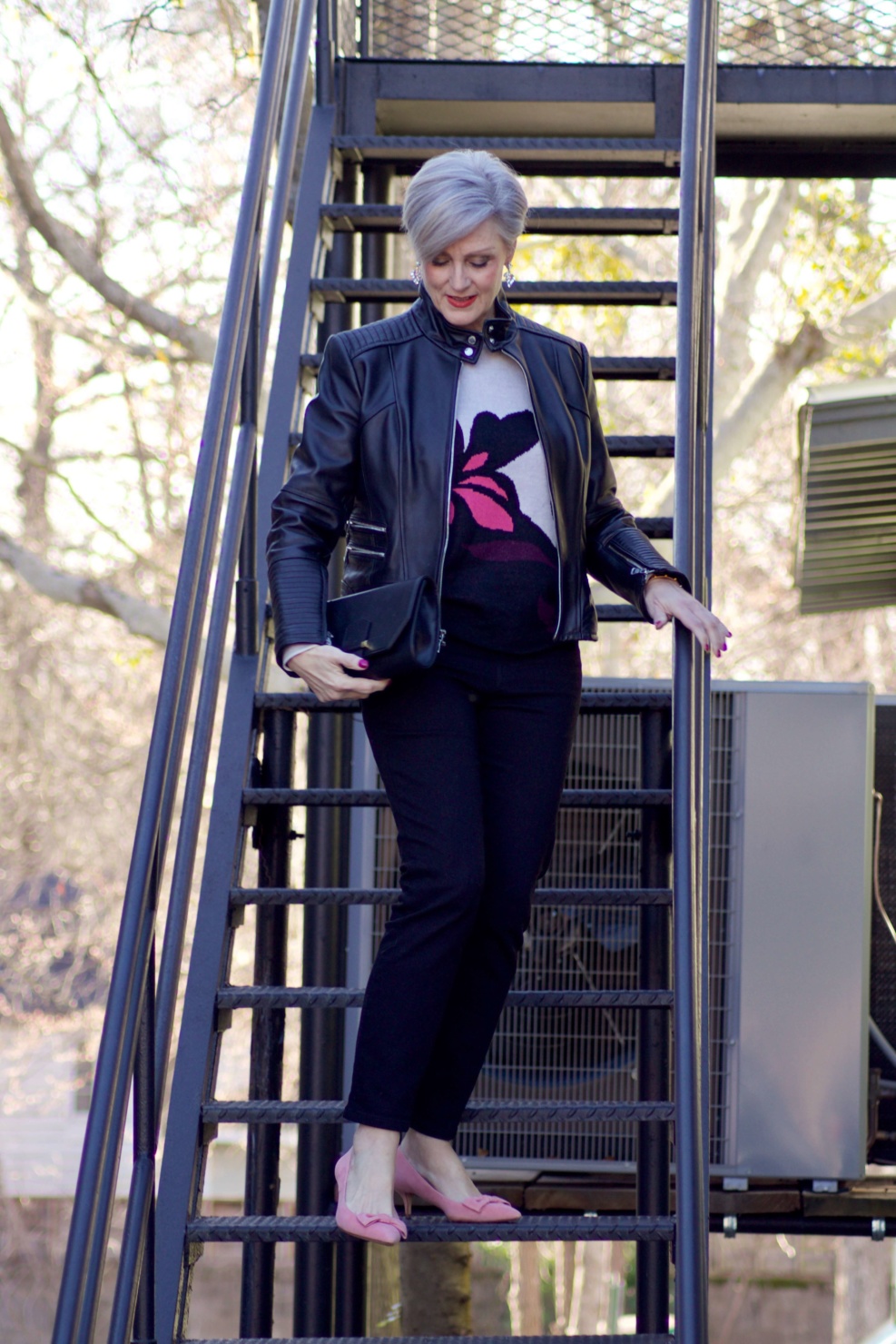 beth from Style at a Certain Age wears a floral jacquard sweater, black skinny jeans, black leather moto jacket and pink suede pumps for date night