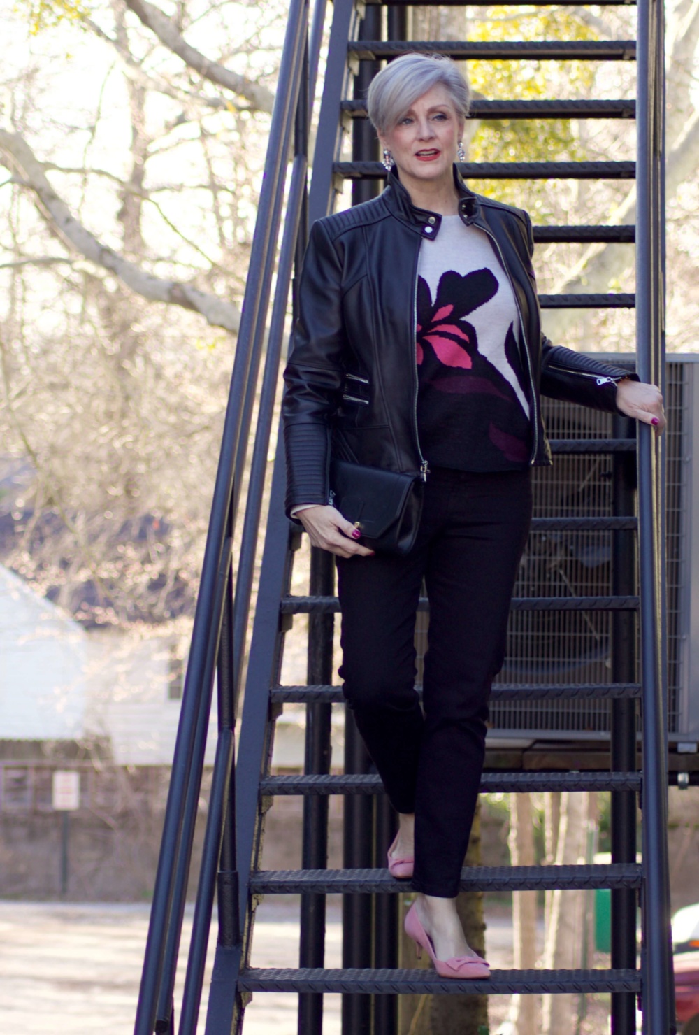 beth from Style at a Certain Age wears a floral jacquard sweater, black skinny jeans, black leather moto jacket and pink suede pumps for date night