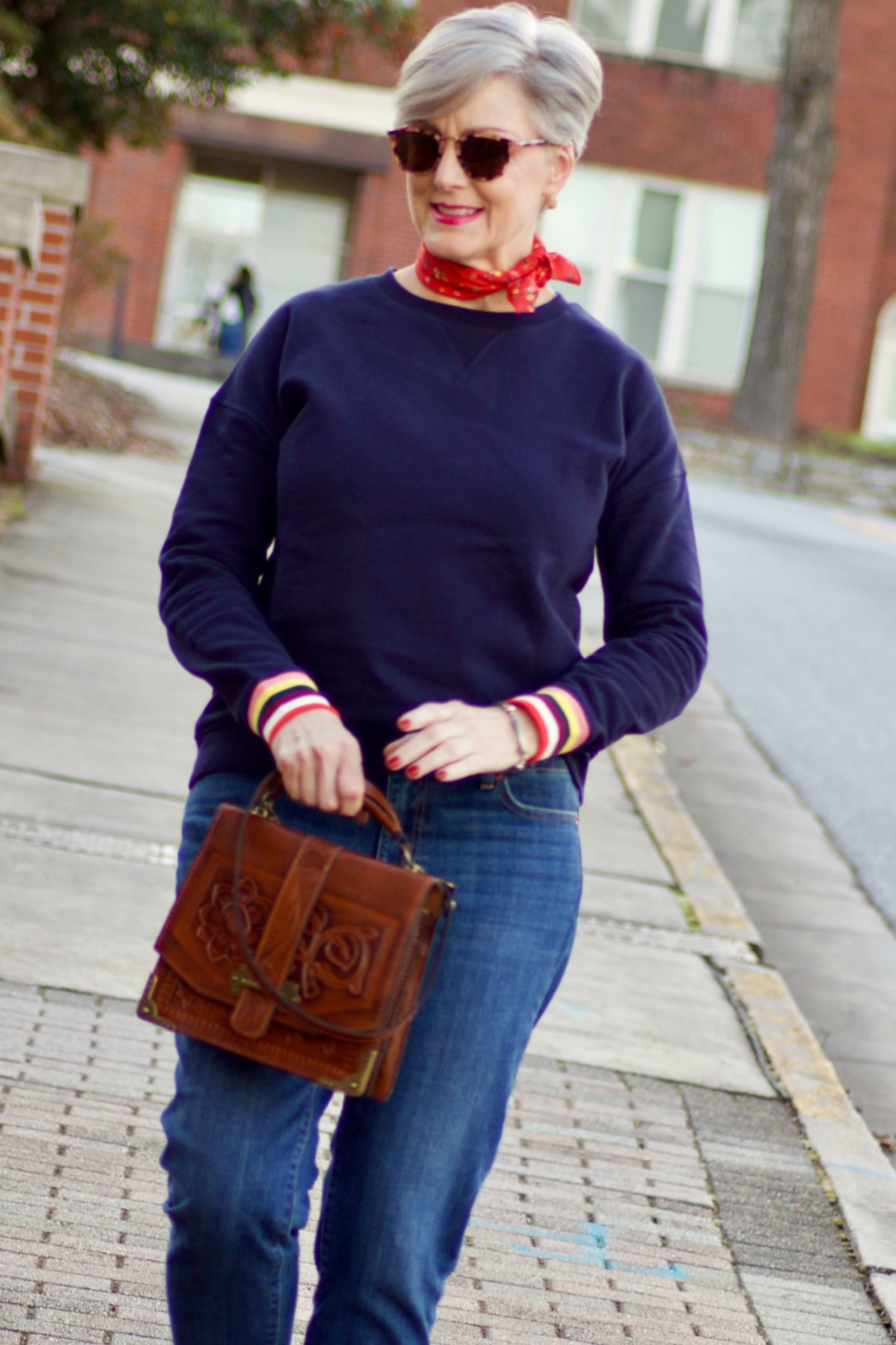 beth from Style at a Certain Age wears a navy blue sweatshirt, blue jeans, Everlane loafers and a J.Crew scarf