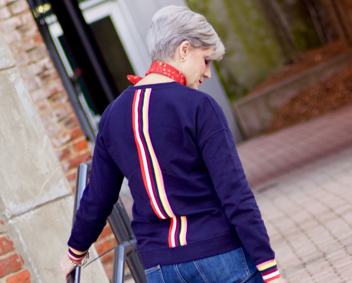 beth from Style at a Certain Age wears a navy blue sweatshirt, blue jeans, Everlane loafers and a J.Crew scarf