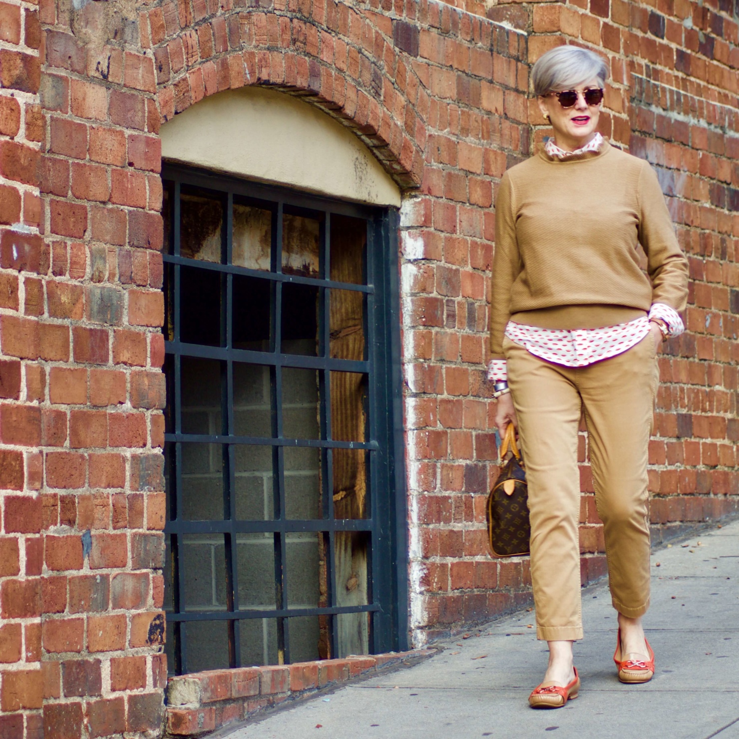 beth from Style at a Certain Age wears a J.Crew camel ruffle neck sweater, slim boy chinos and a Boden modern classic shirt with a bold print.