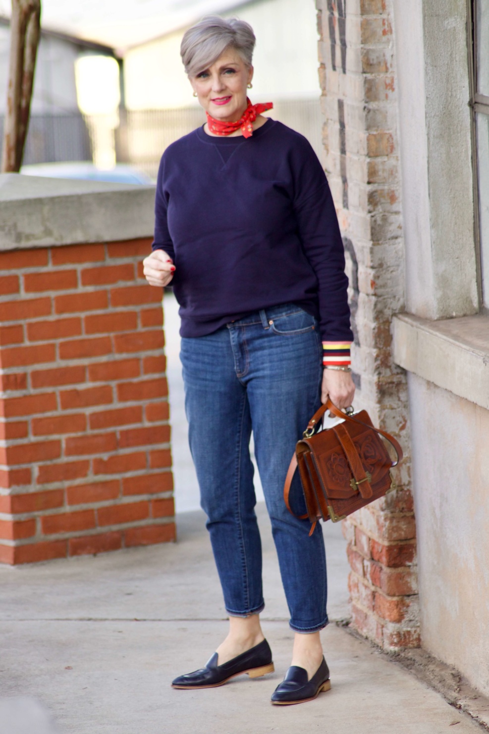 beth from Style at a Certain Age wears a navy blue sweatshirt, blue jeans, Everlane loafers and a J.Crew scarf