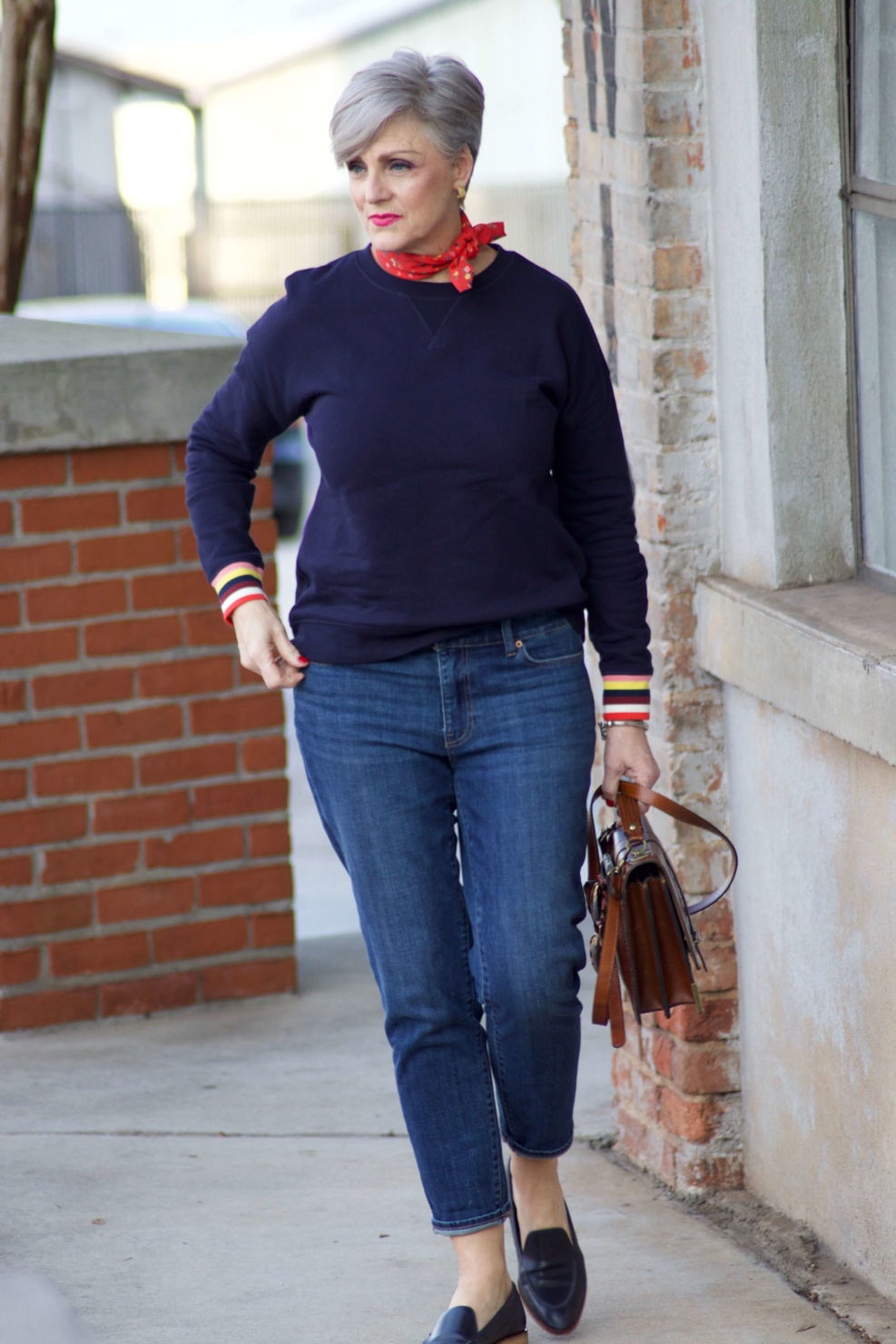 beth from Style at a Certain Age wears a navy blue sweatshirt, blue jeans, Everlane loafers and a J.Crew scarf