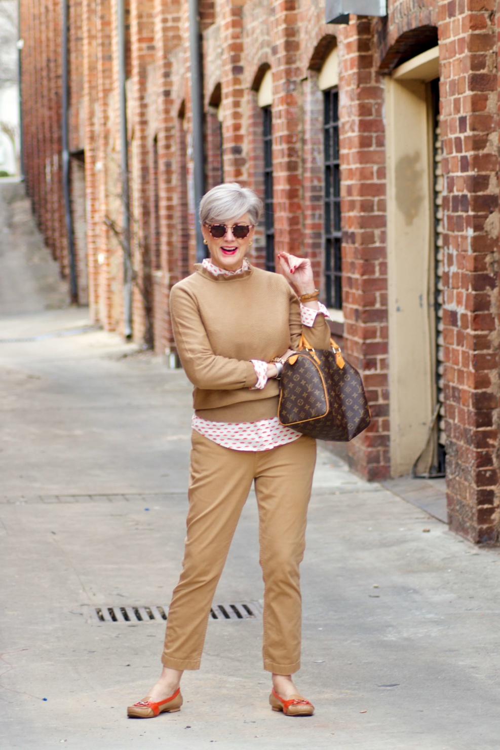 beth from Style at a Certain Age wears a J.Crew camel ruffle neck sweater, slim boy chinos and a Boden modern classic shirt with a bold print.