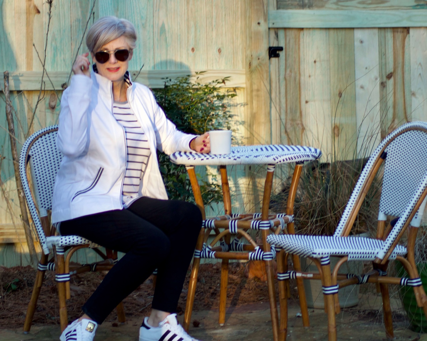 beth from Style at a Certain Age wears a stripe t-shirt, black yoga pants, and white track jacket