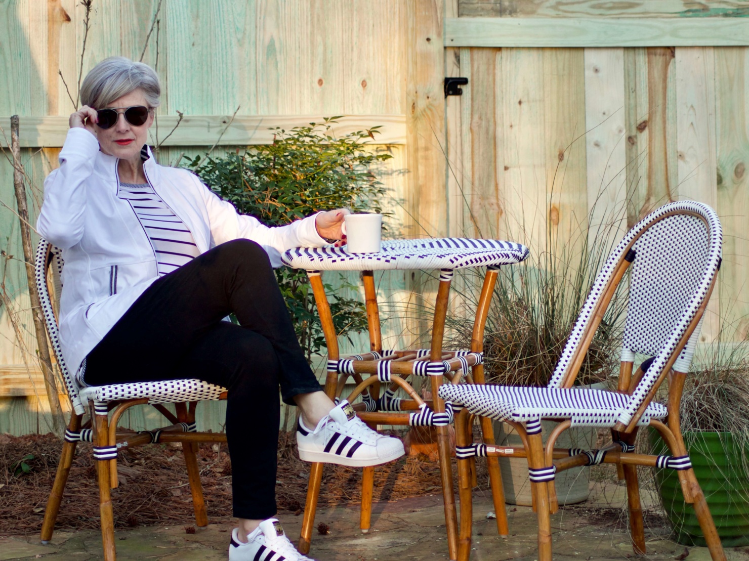 beth from Style at a Certain Age wears a stripe t-shirt, black yoga pants, and white track jacket