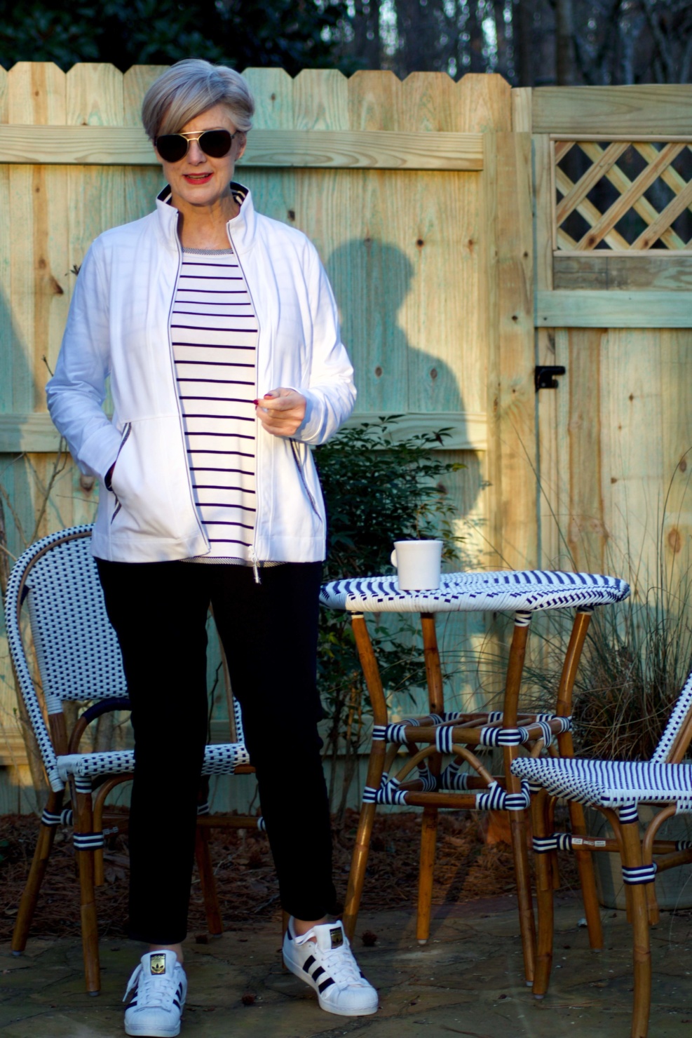 beth from Style at a Certain Age wears a stripe t-shirt, black yoga pants, and white track jacket