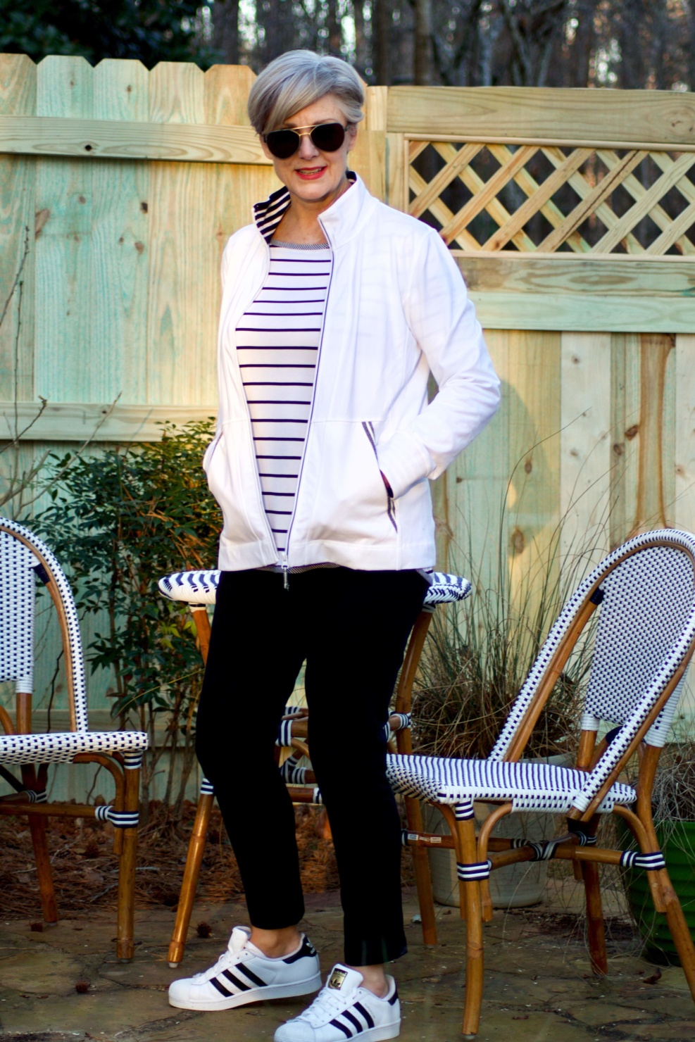 beth from Style at a Certain Age wears a stripe t-shirt, black yoga pants, and white track jacket