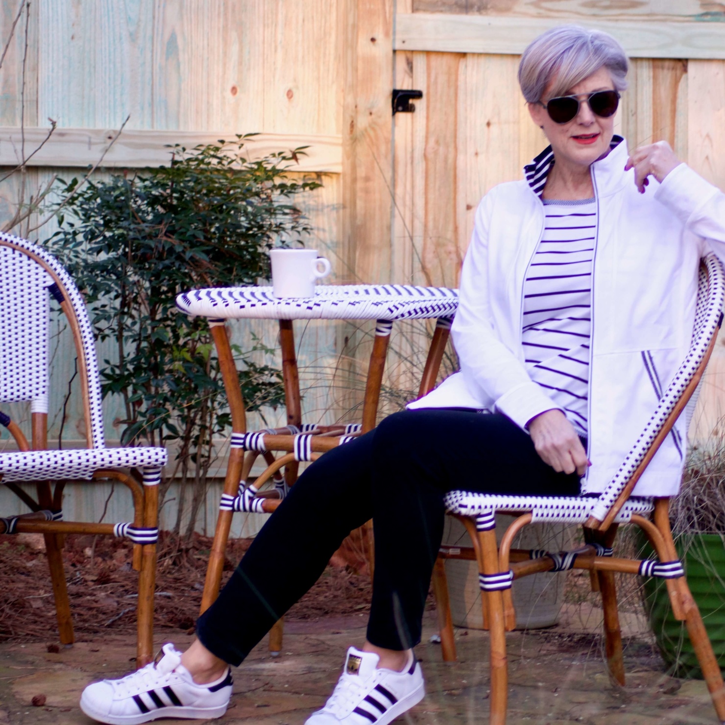 beth from Style at a Certain Age wears a stripe t-shirt, black yoga pants, and white track jacket