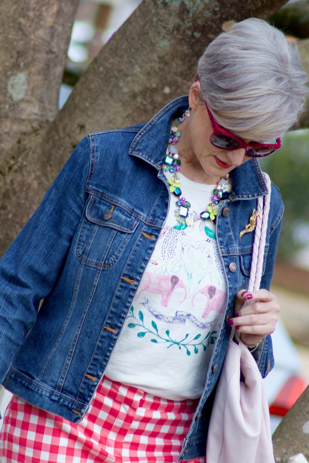 beth from Style at a Certain Age wears pink gingham pants, graphic tee, and denim jacket