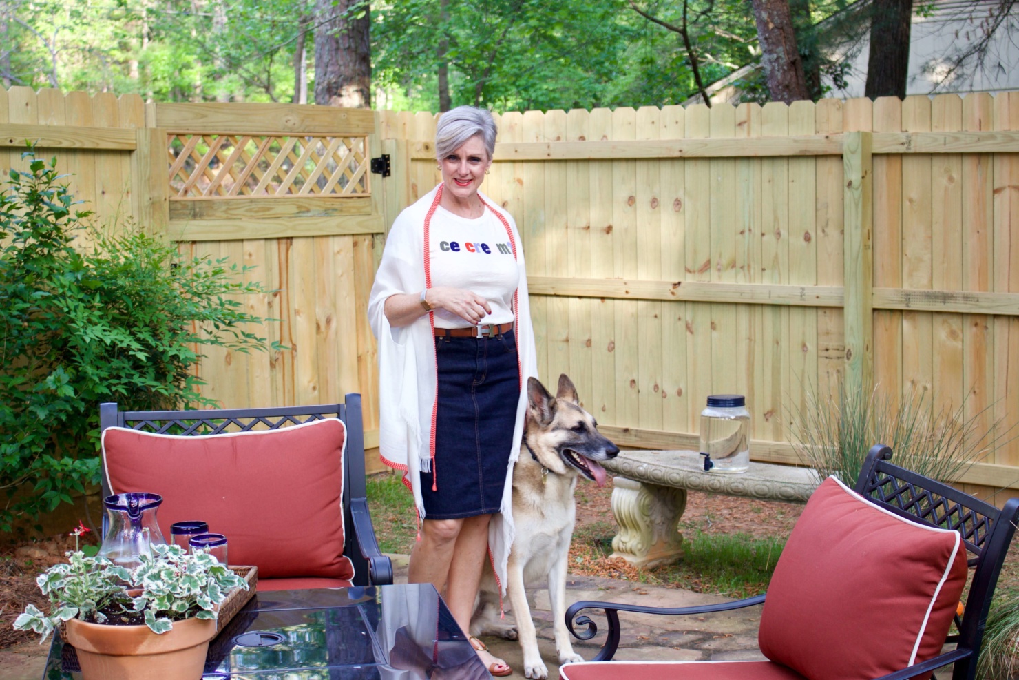 beth from Style at a Certain Age wears a J.Crew graphic tee, jean skirt, lightweight cape scarf, and Tory Burch sandals