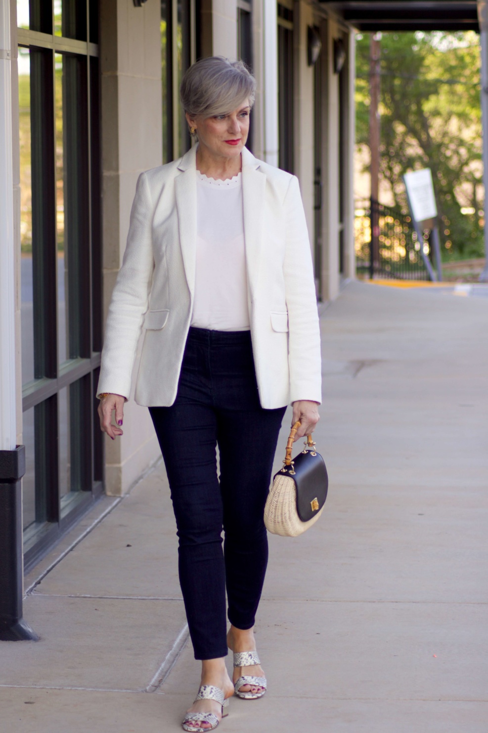 beth from Style at a Certain Age wears a textured ivory blazer, ivory scalloped shell, dark rinse skinny jeans, snakeskin sandals and wicker handbag