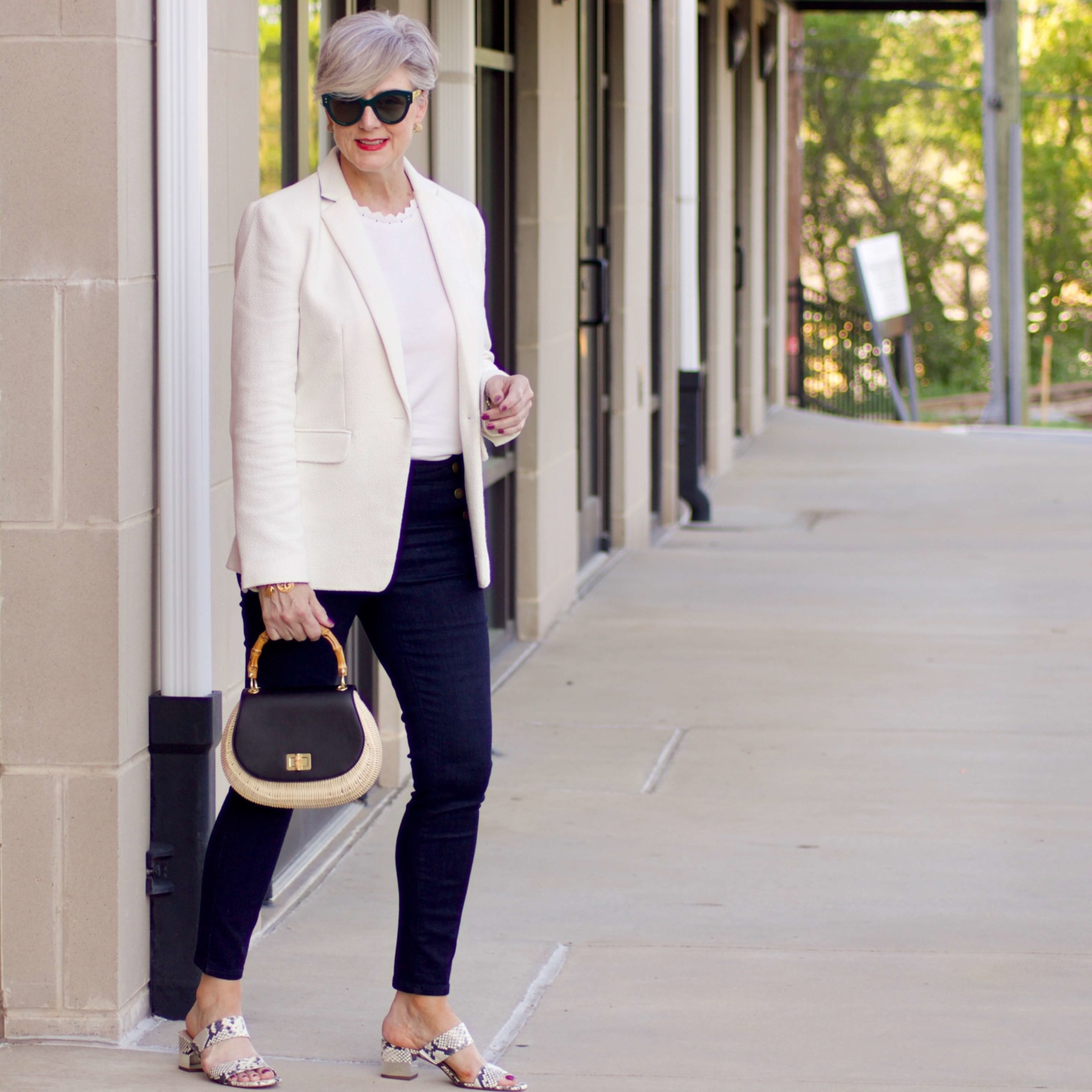 beth from Style at a Certain Age wears a textured ivory blazer, ivory scalloped shell, dark rinse skinny jeans, snakeskin sandals and wicker handbag