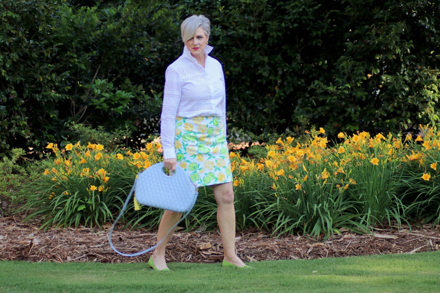 beth from Style at a Certain Age wears a lemon print skirt, eyelet blouse, pointy-toed flats and o-bag